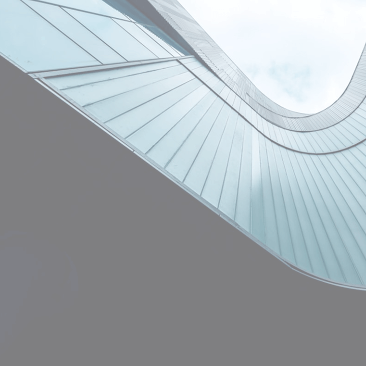 Abstract upward view of a modern curved glass façade curving against a cloudy sky.